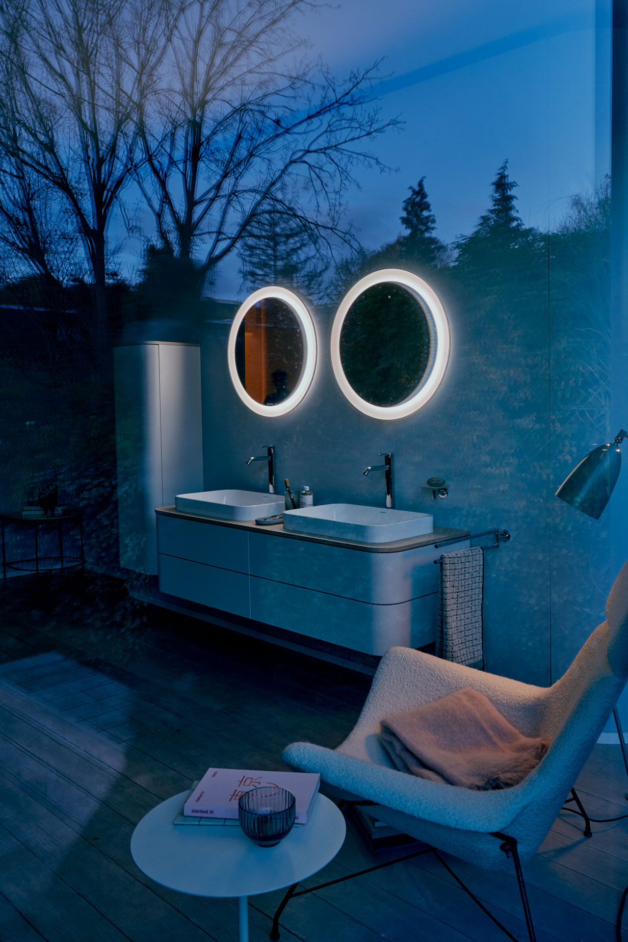 Dark bathroom with two round and lighted mirrors
